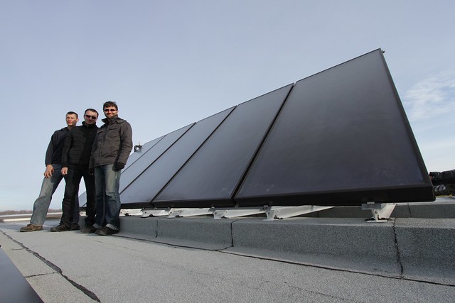 Ryan Hammond of the Executive Flight Centre, Bruce Ganske of Magnum Mechanical Systems and Alex Polkovsky of NuEnergy with the solar thermal collectors on the roof of Terminal 4 at the Edmonton International Airport.