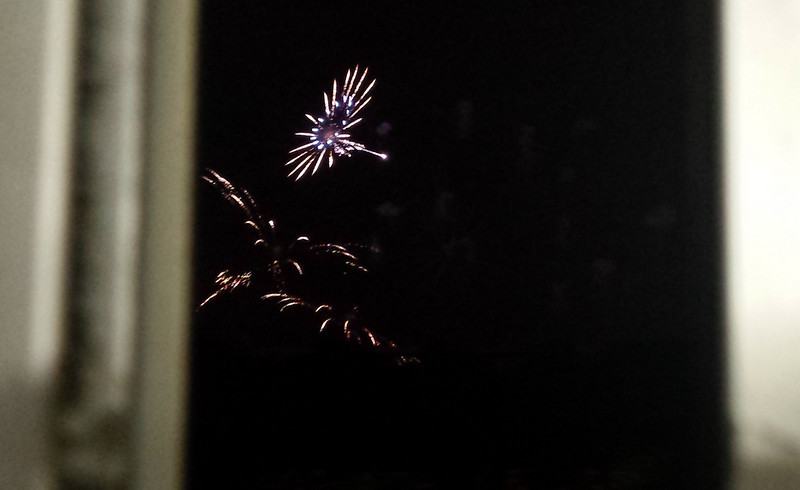 fireworks in the distance, framed by metal window sills
