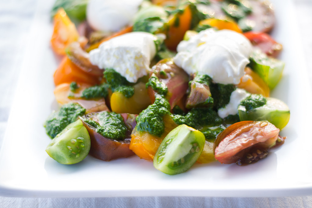 A slight twist on the classic salad, this Burrata Caprese boasts colorful wedges of heirloom tomatoes, creamy burrata cheese and a fresh and bright herb oil drizzled on top.  